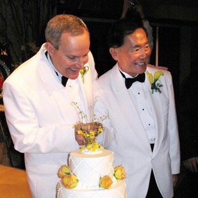 Brad Altman and George Takei cutting their wedding cake.